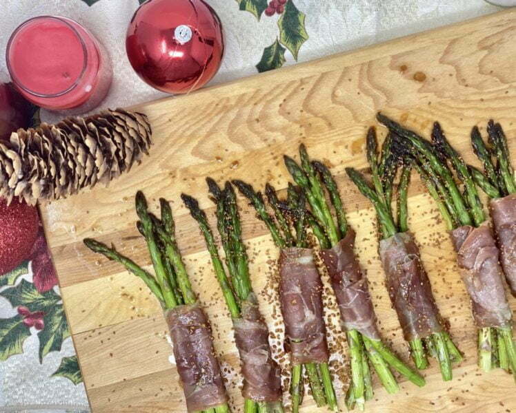 Asperges enroulées de proscuitto et caméline sur planche de bois